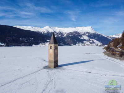 Il campanile sommerso del lago di Resia con la neve visto dal drone