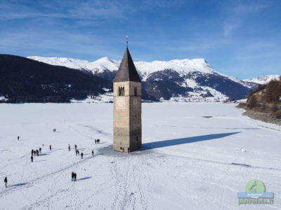 Il campanile sommerso del lago di Resia con la neve visto dal drone