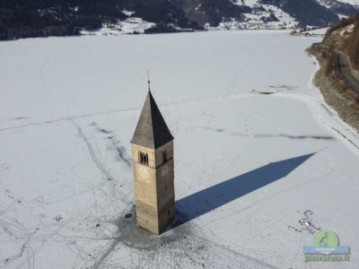 Il campanile sommerso del lago di Resia con la neve visto dal drone